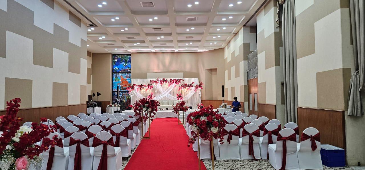 Indoor banquet hall setup with elegant chairs and red carpet walkway